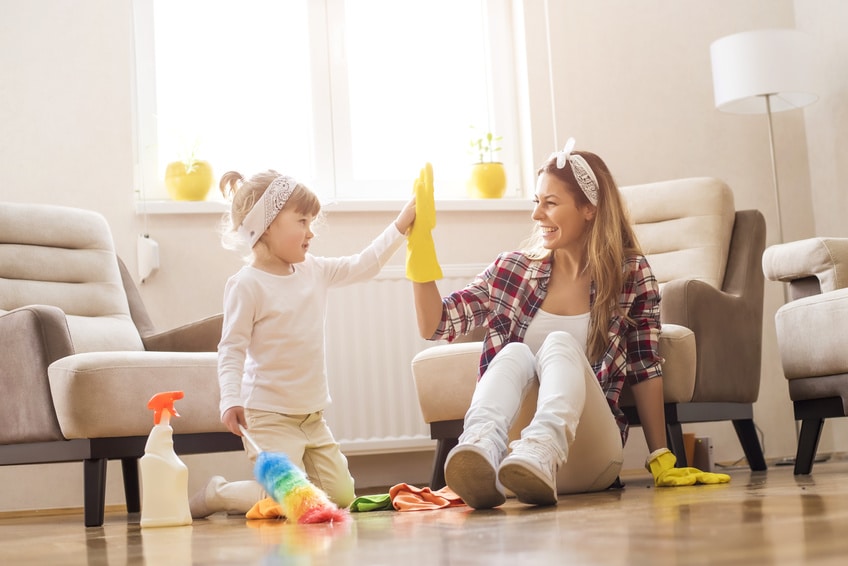 Daughter and mother cleaning home together and having fun.